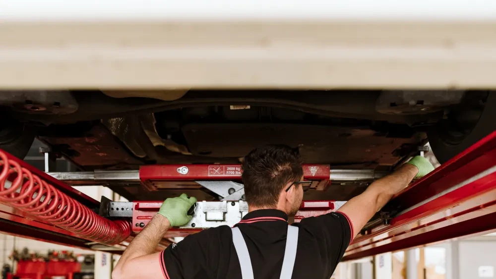 Monteur inspecteert onderzijde auto
