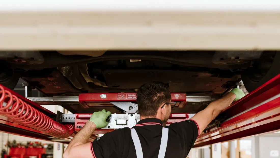 Monteur inspecteert onderzijde auto